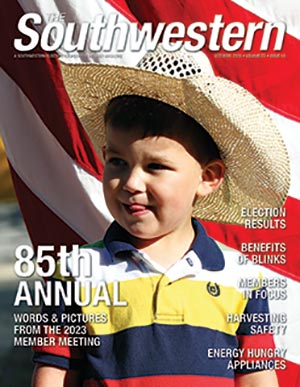 Young cowboy stands before a flag at Southwestern's 85th annual meeting