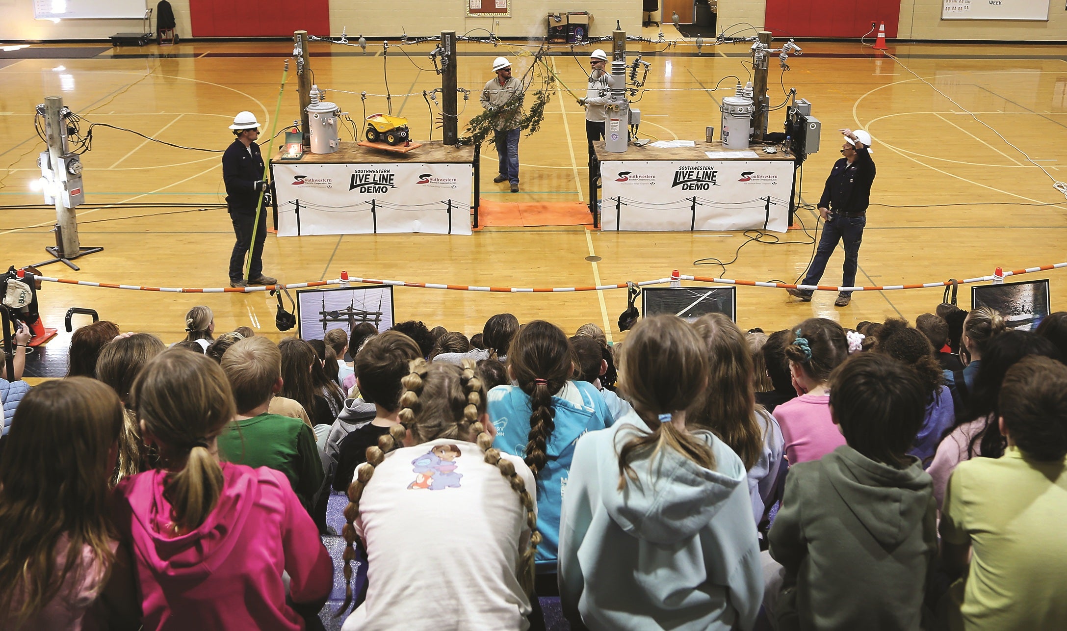 A line crew demonstrates the dangers of electricity to a group of school-aged children.