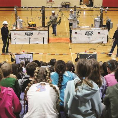 A line crew demonstrates the dangers of electricity to a group of school-aged children.